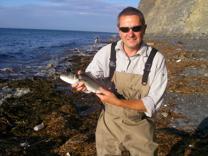 Dave holds a modest bass while Nigel, in the background, plays another fish on the fly gear.