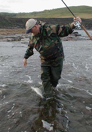 John reaches down to pick up his fish.