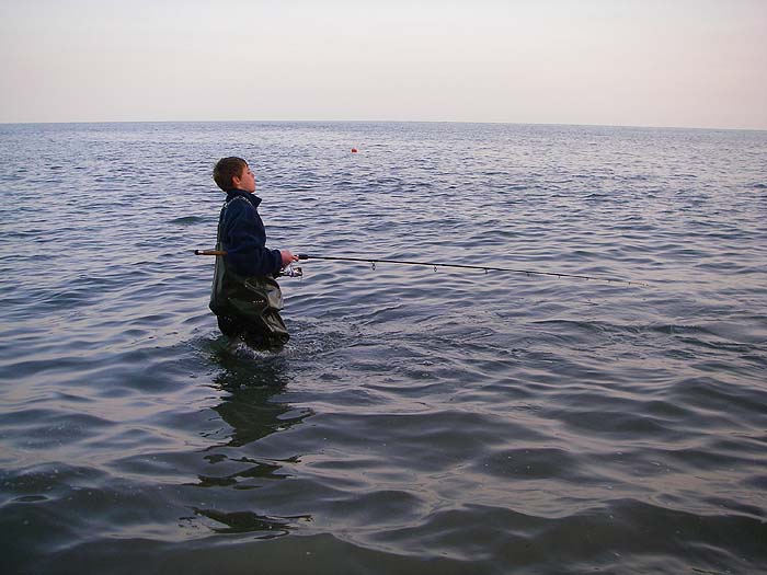 Grandson and fishing buddy Ben tries to lure a bass from the shallow water.