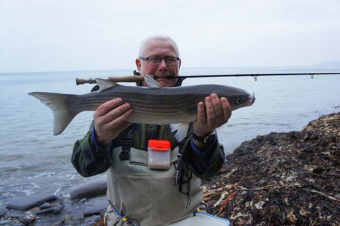 Nigel shows off his catch with the fly rod firmly gripped between his teeth..