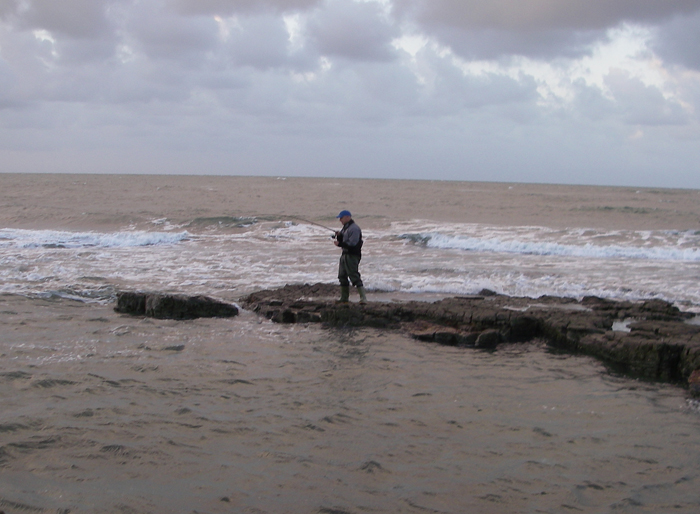 His rod begins to bend to the hooked bass.