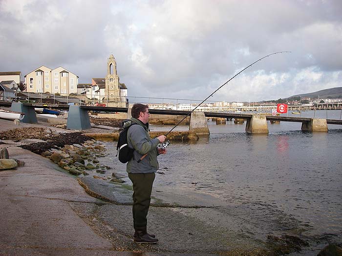 Ben's spinning rod bent (but not too much) into the bass. The lifeboat slip is in the background.
