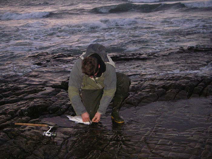 Ben kneels to unhook his catch.