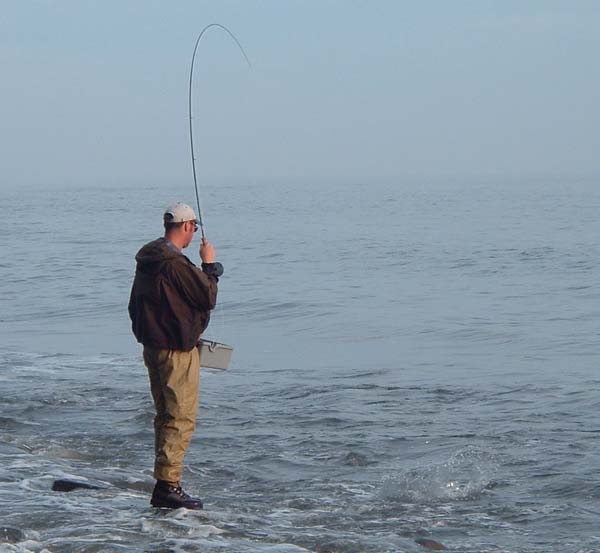 Silas into a bass on his fly gear.  The fish is splashing close to his feet.